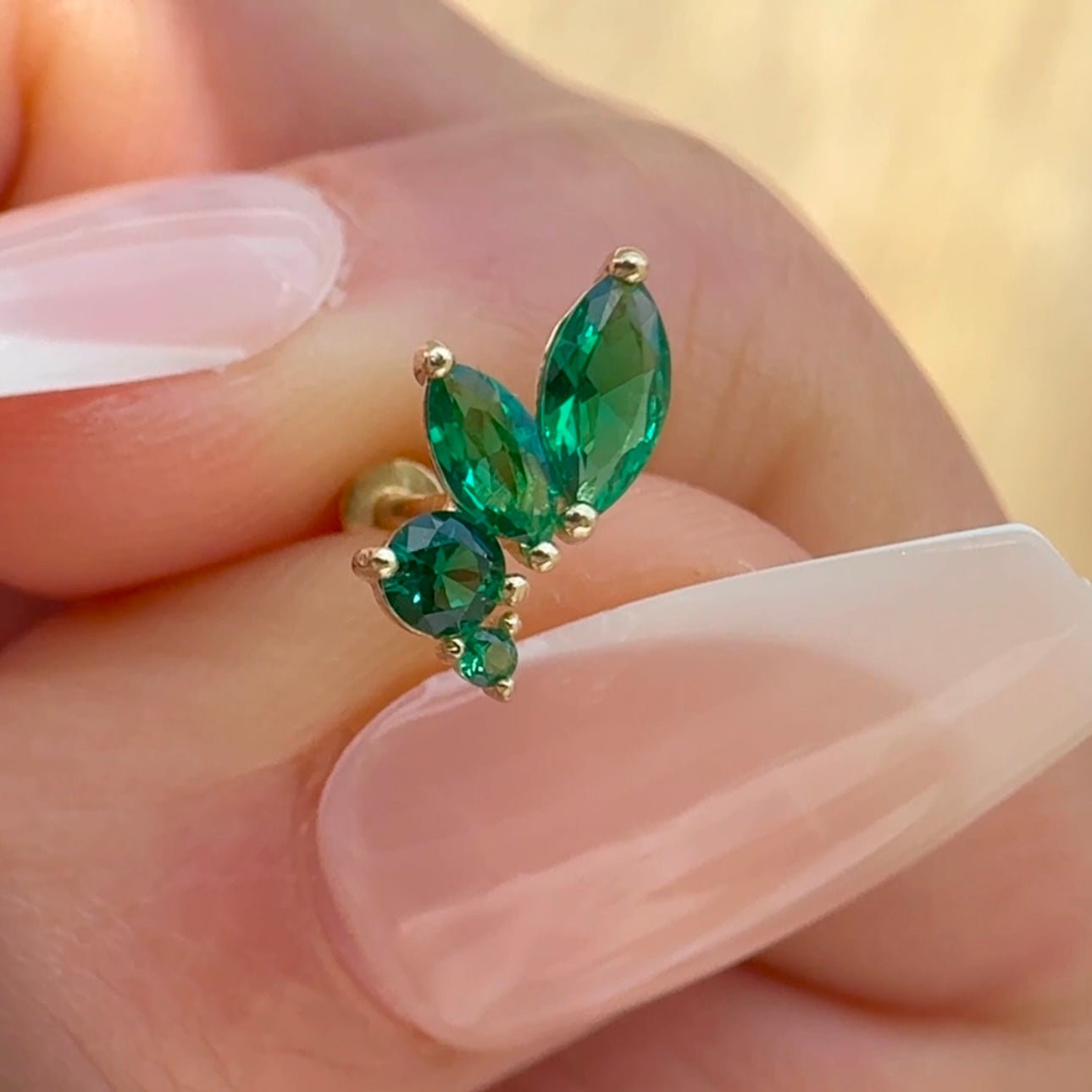 a close up of a person's hand holding a green ring