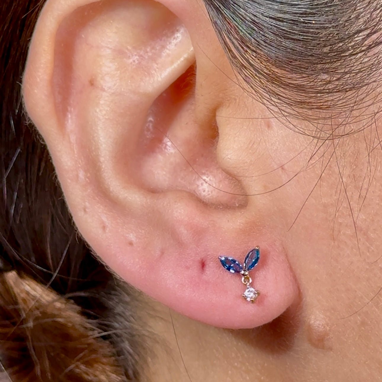 a close up of a person's ear with a butterfly piercing