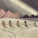 a row of different colored diamond studs on a white surface