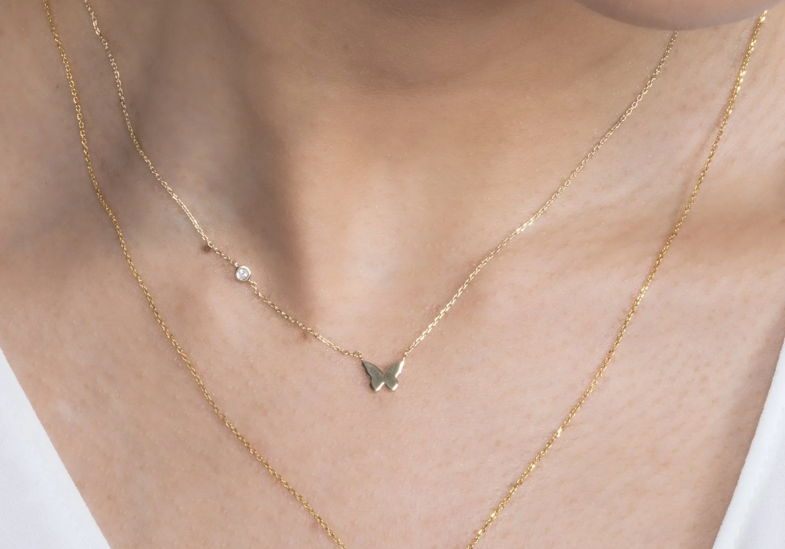 A woman wearing the Bubble Butterfly and Diamond Station Necklace