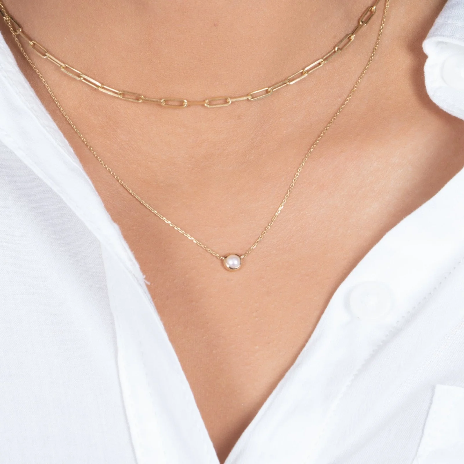A woman wearing the Freshwater Pearl Station Necklace Bezel Set in 14k Gold