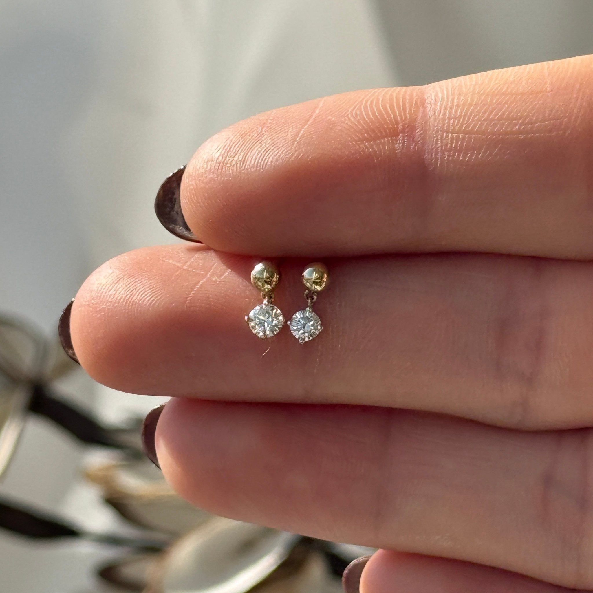 a person's hand holding a pair of diamond earrings