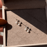 a woman's hand holding a pair of earrings in a box