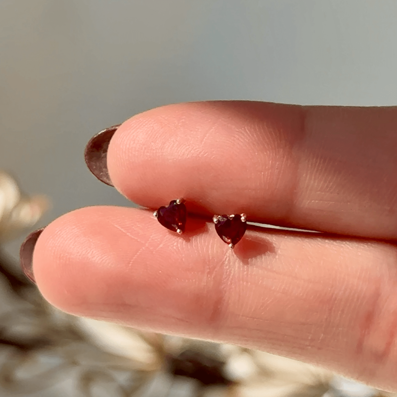 a person's hand holding a tiny heart shaped ring