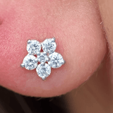 a close up of a person's ear with a flower shaped earring