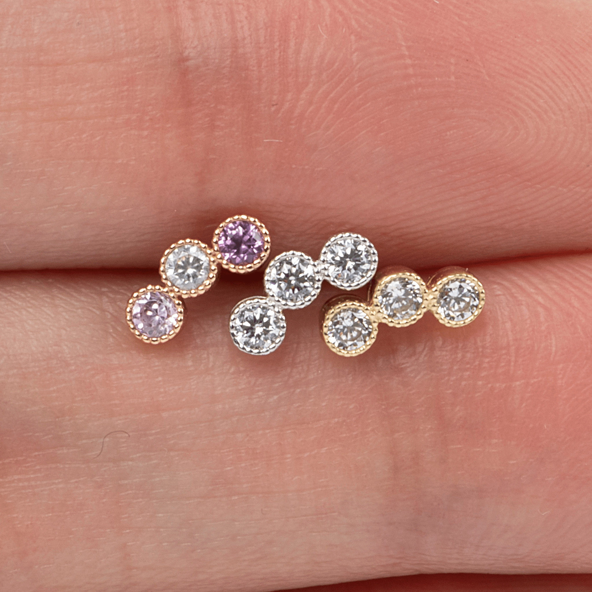 a person's hand holding three different colored stones