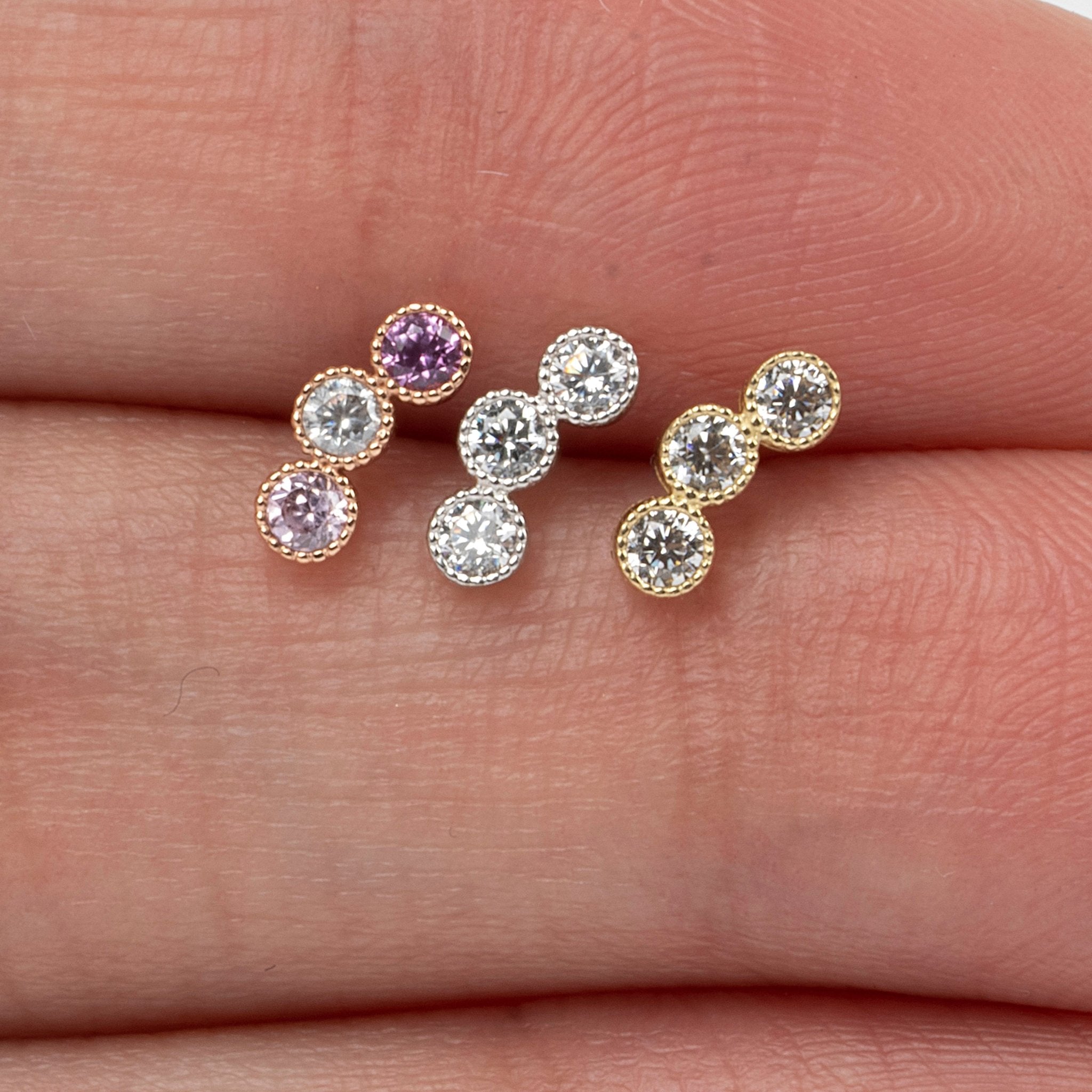 a person's hand holding three different colored stones