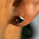 a close up of a person wearing a black diamond earring