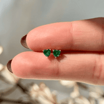 a person's hand holding a pair of green earrings