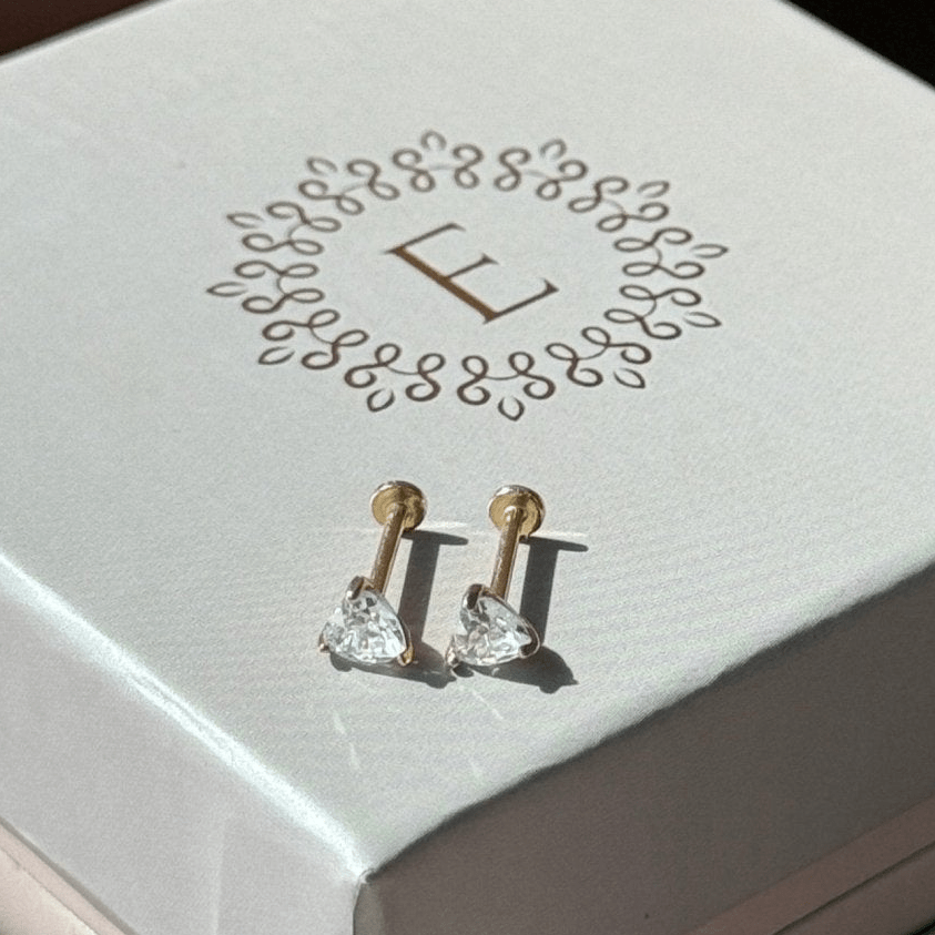 a pair of earrings sitting on top of a white box