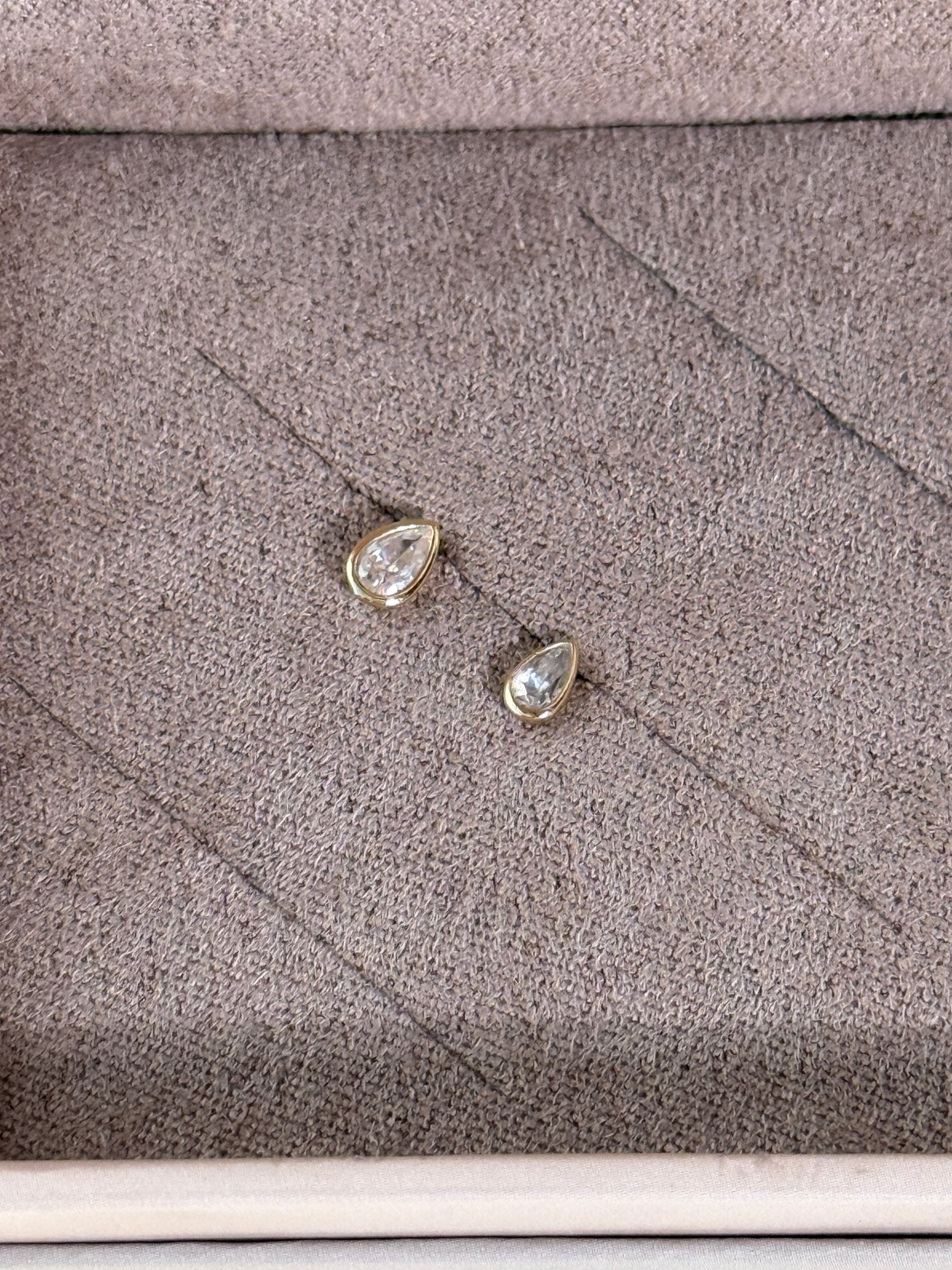 a close up of a pair of earrings on a cushion