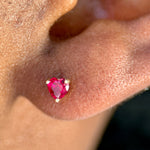 a close up of a person's ear with a pink stone