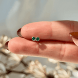 a woman's hand holding a tiny green ring