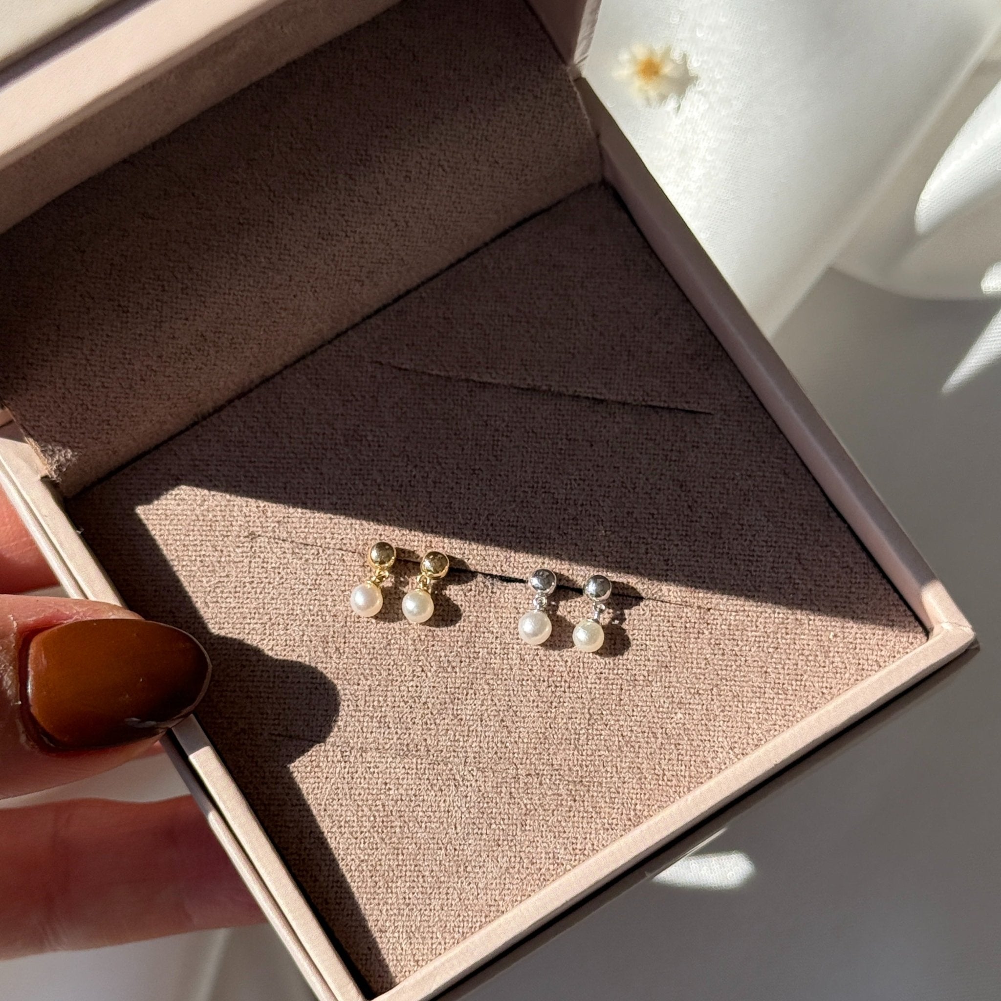 a person holding a pair of earrings in a box