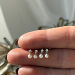 a woman's hand holding a ring with pearls on it