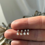 a woman's hand holding a ring with pearls on it