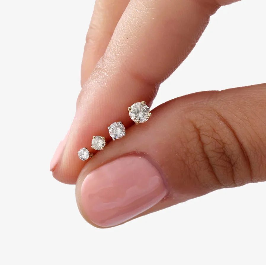 a person holding all carat sizes od the diamond flat back stud earrings