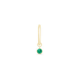 a gold earring with a green stone