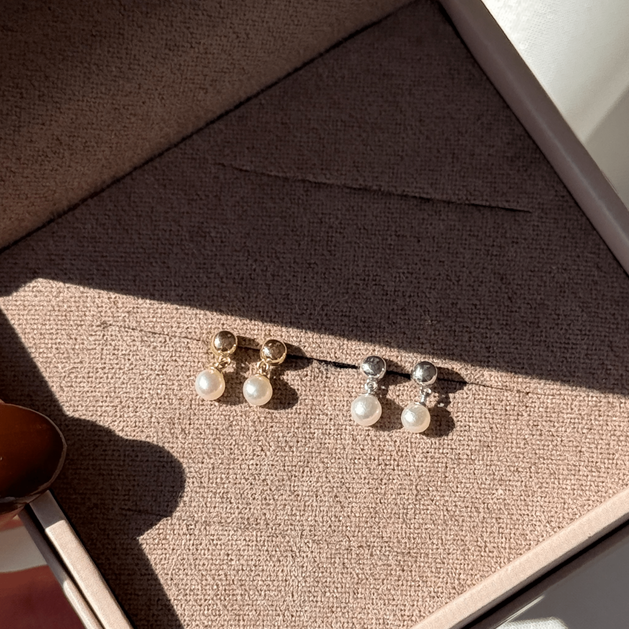 a person holding a pair of earrings in a box