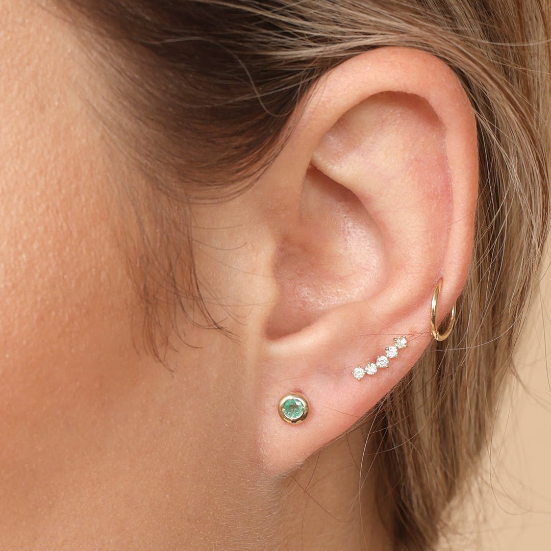 a close up of a woman's ear with a green stone