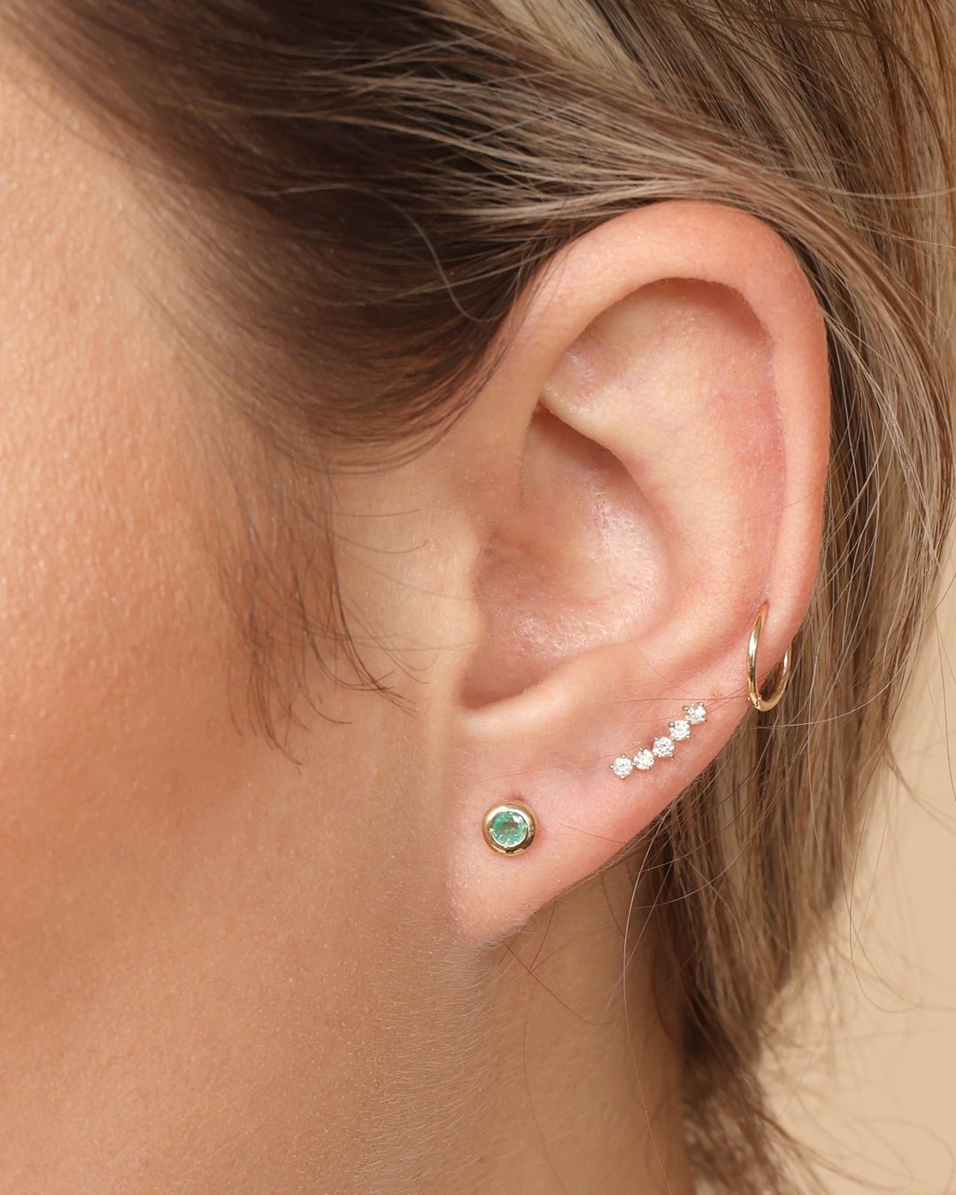 a close up of a woman's ear with a green stone