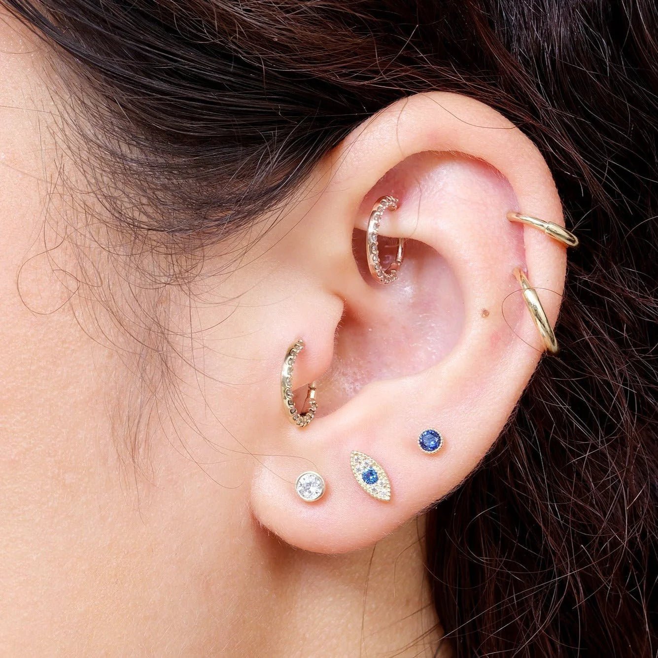 an ear styled with cubic zirconia studs and an evil eye diamond stud