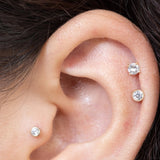 an ear up close with three cubic zirconia stud earrings