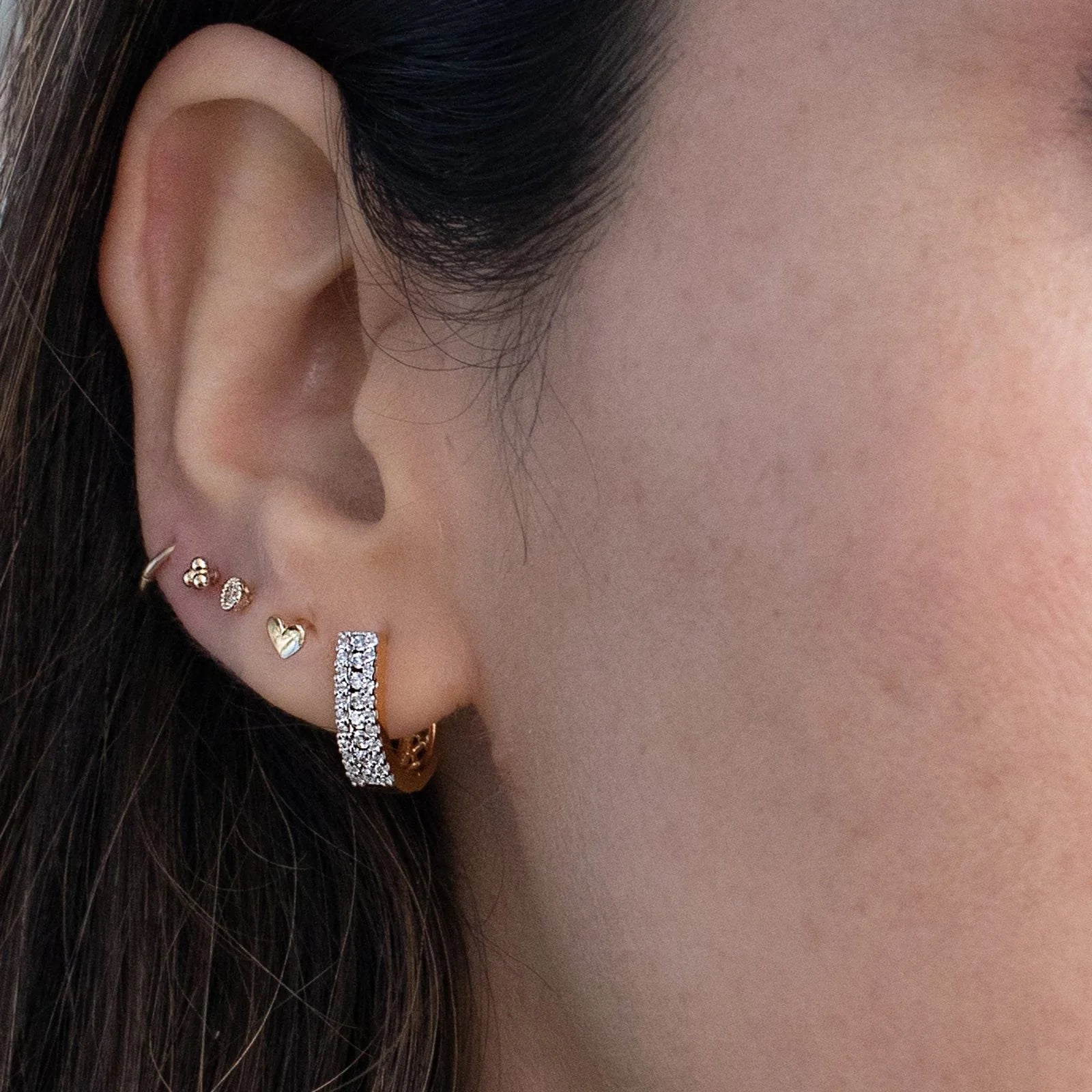 an ear styled with a diamond pave huggie and gold studs.