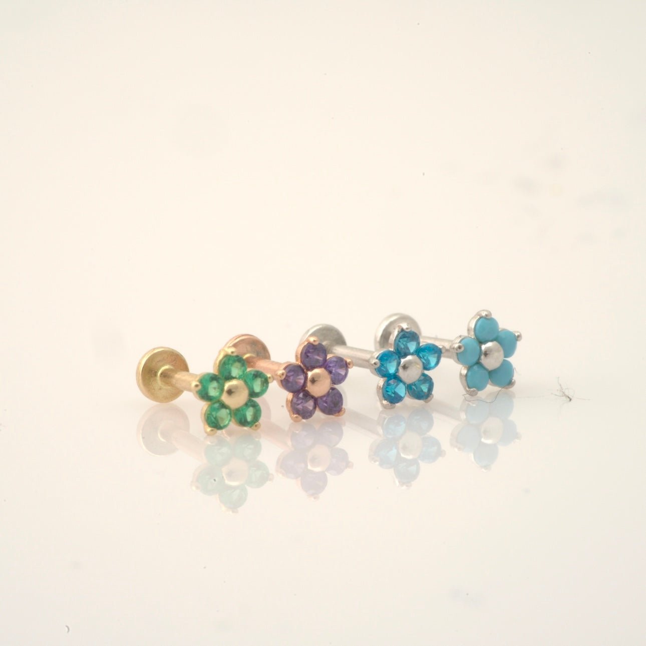 three different colored flower shaped studs on a white surface