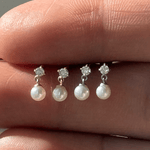 a woman's hand holding a ring with pearls on it