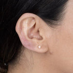 a model wearing a single pink opal stud earring