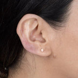 a model wearing a single pink opal stud earring