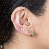 model wearing multiple diamond flat back studs with gold hoops